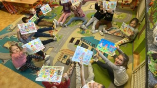 Uczniowie pokazują swoje namalowane prace z okazji Dnia Kredki