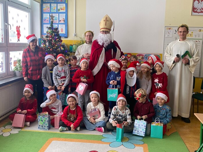 Uczniowie z oddziałów przedszkolnych pozują do zdjęcia ze swoimi prezentami, które otrzymały od świętego Mikołaja