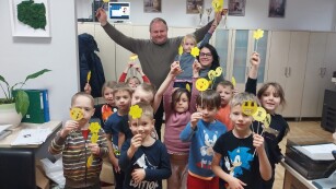 Uczniowie oddziału przedszkolnego świętują dzień życzliwości i pozdrowień z Panią Dyrektor szkoły oraz Panem Kierownikiem gospodarczym. Wszyscy trzymają karteczki z żółtymi uśmiechami
